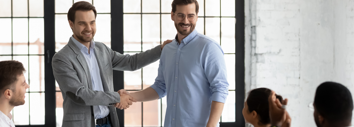 Prinsjesdag werkgevers; werkgever geeft staand een personeelslid een hand tijdens een vergadering met collega's