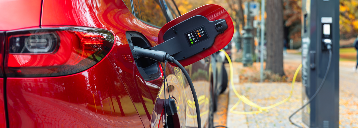 Rode SUV elektische plugin hybride staat geparkeerd bij een oplaadstation