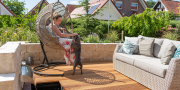 Vrouw zit in een stoel op de veranda en aait de hond 